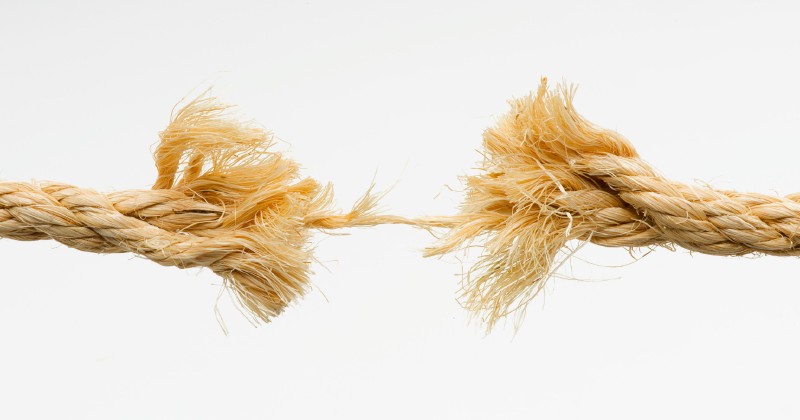 A frayed rope breaking in the middle against a white background